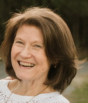 A woman smiling outdoors, representing NAHMA's housing and community services.